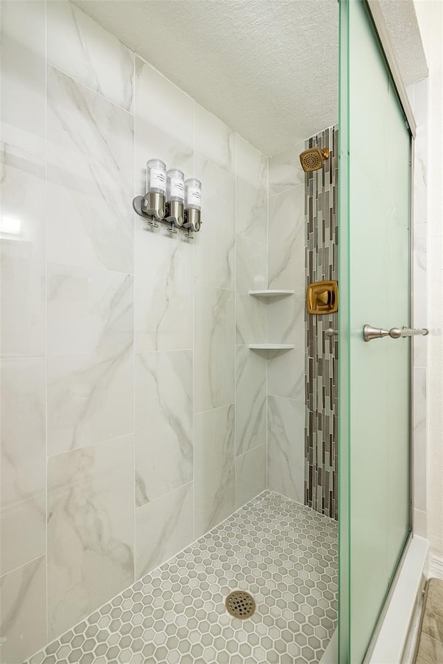 bathroom featuring a textured ceiling and a tile shower