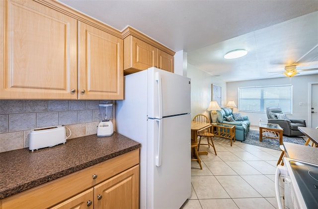 kitchen featuring white fridge, light tile flooring, stove, ceiling fan, and backsplash