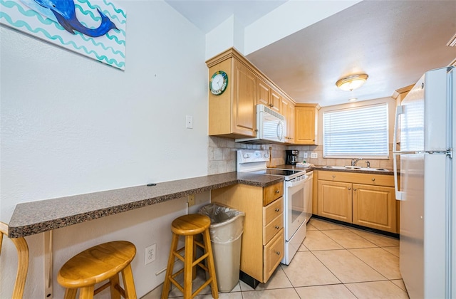 kitchen featuring a kitchen breakfast bar, light tile flooring, tasteful backsplash, white appliances, and sink