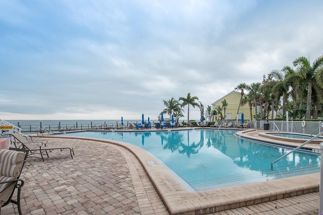 view of pool with a community hot tub, a water view, and a patio