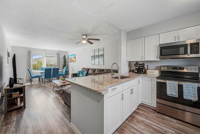 kitchen featuring ceiling fan, kitchen peninsula, white cabinetry, appliances with stainless steel finishes, and sink