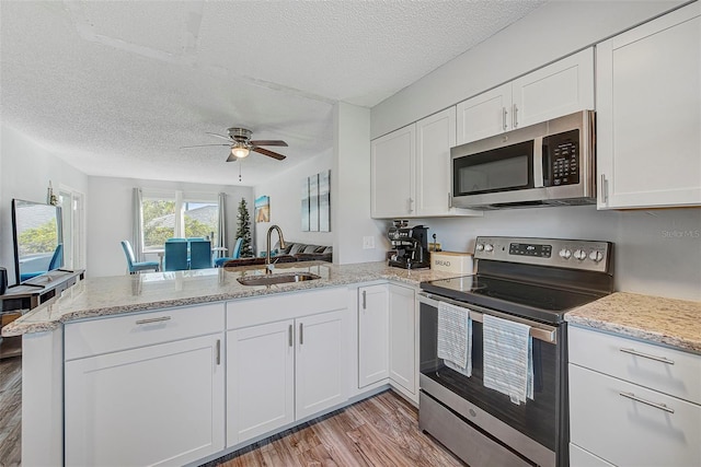 kitchen with kitchen peninsula, ceiling fan, light hardwood / wood-style floors, sink, and stainless steel appliances