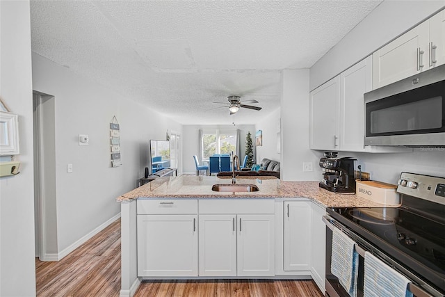 kitchen featuring white cabinets, stainless steel appliances, ceiling fan, and kitchen peninsula