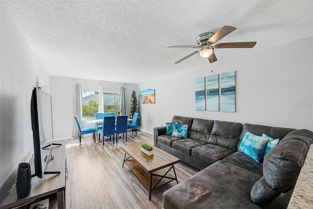 living room featuring a textured ceiling, ceiling fan, and light hardwood / wood-style flooring