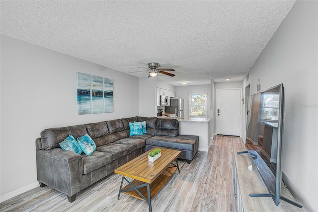 living room featuring a textured ceiling, ceiling fan, and light hardwood / wood-style flooring