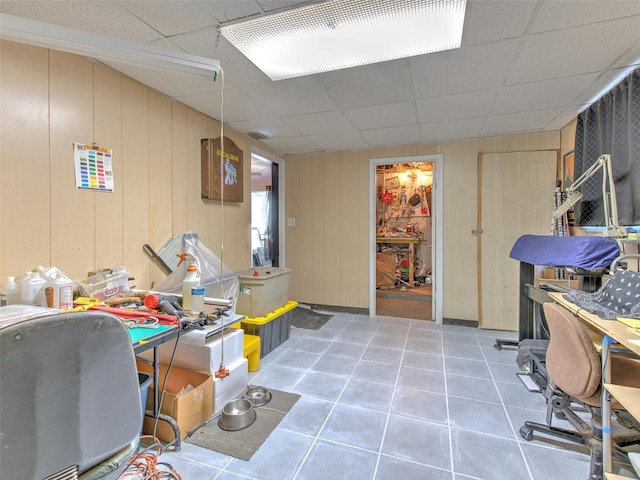 interior space featuring wooden walls, tile floors, and a drop ceiling