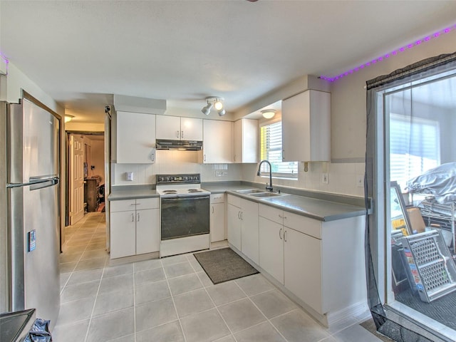 kitchen featuring white electric stove, backsplash, stainless steel refrigerator, light tile flooring, and white cabinetry