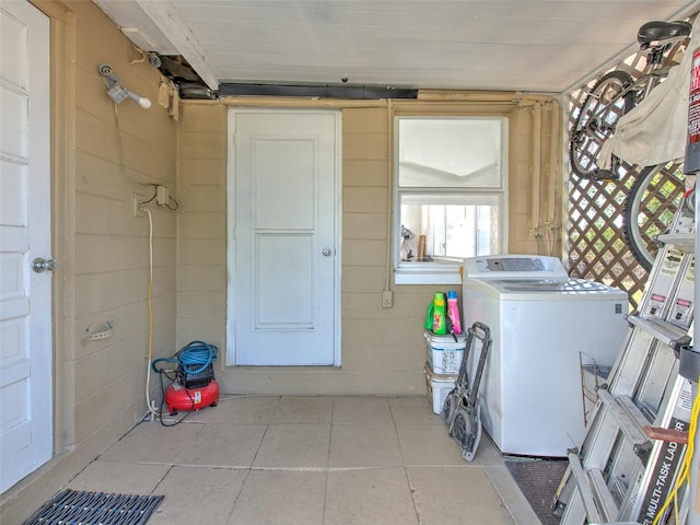 clothes washing area with washer / clothes dryer and light tile floors