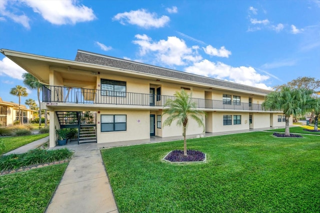 back of property with a balcony and a lawn