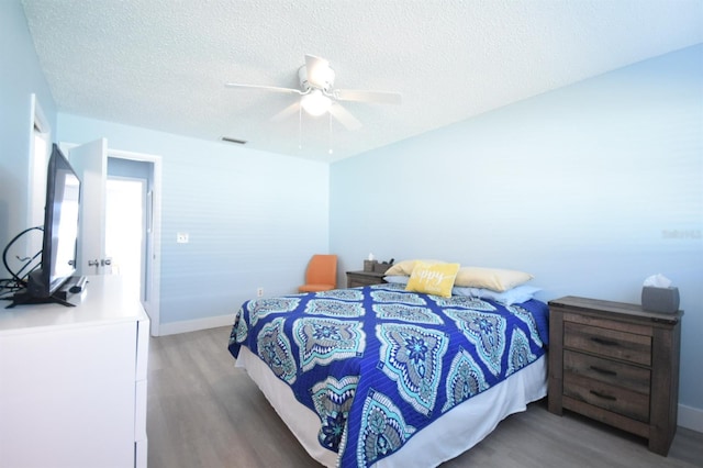 bedroom with hardwood / wood-style flooring, ceiling fan, and a textured ceiling