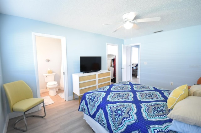 bedroom featuring a walk in closet, ensuite bathroom, ceiling fan, hardwood / wood-style floors, and a closet