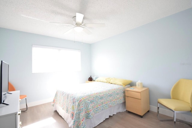 bedroom with a textured ceiling, light hardwood / wood-style floors, and ceiling fan