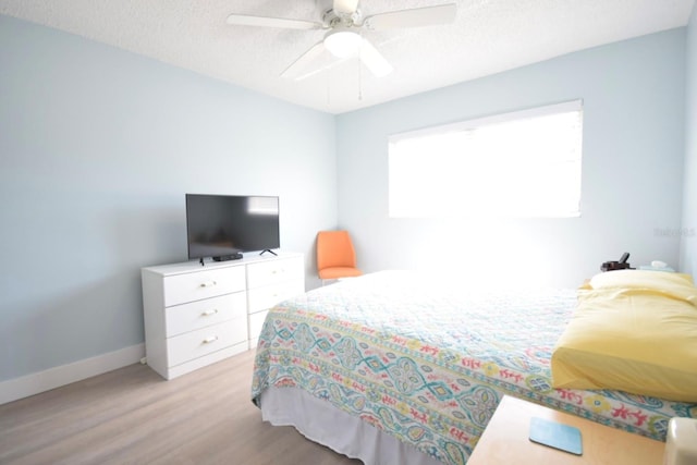 bedroom featuring ceiling fan, light wood-type flooring, and a textured ceiling