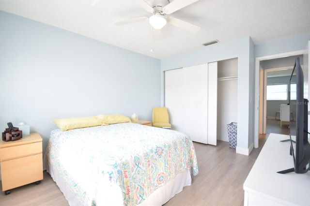 bedroom with ceiling fan, light wood-type flooring, a textured ceiling, and a closet