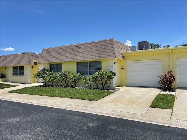 ranch-style home featuring central AC unit and a garage