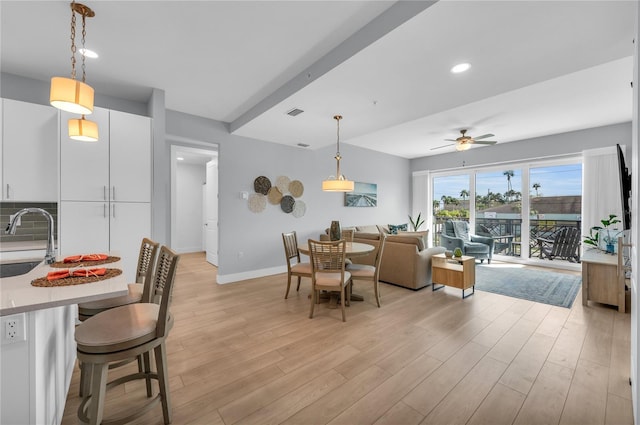 dining space with ceiling fan, light wood-type flooring, and sink