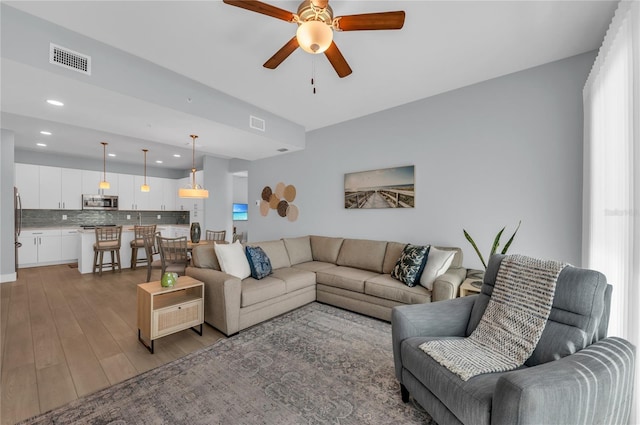 living room with light hardwood / wood-style floors and ceiling fan