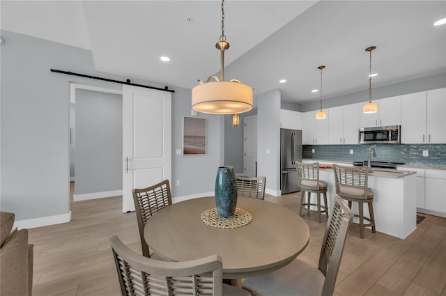 dining area with a barn door and light hardwood / wood-style floors