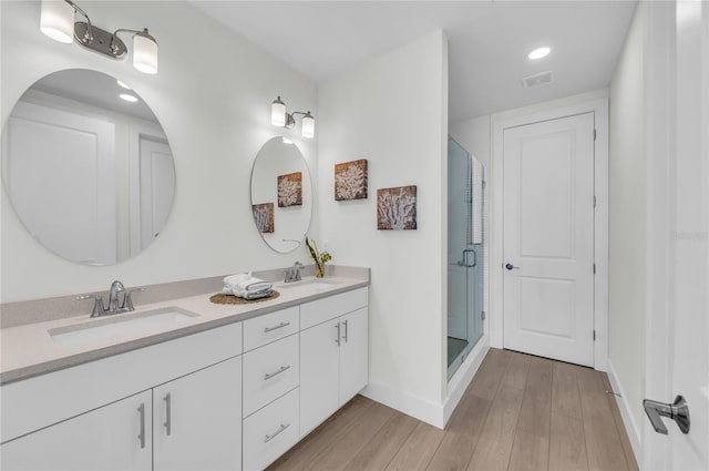 bathroom featuring walk in shower, hardwood / wood-style floors, dual sinks, and large vanity