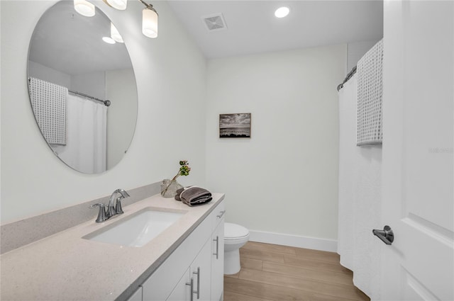 bathroom featuring hardwood / wood-style floors, vanity with extensive cabinet space, and toilet