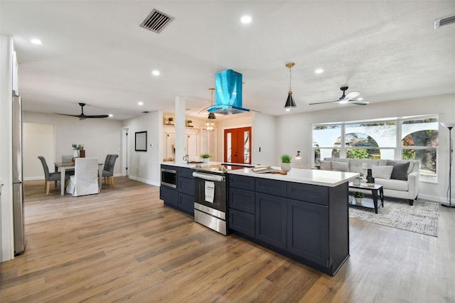 kitchen featuring ceiling fan, a center island, hardwood / wood-style floors, decorative light fixtures, and appliances with stainless steel finishes