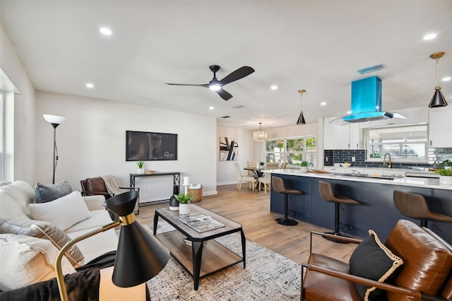 living room with light hardwood / wood-style floors, ceiling fan, and sink