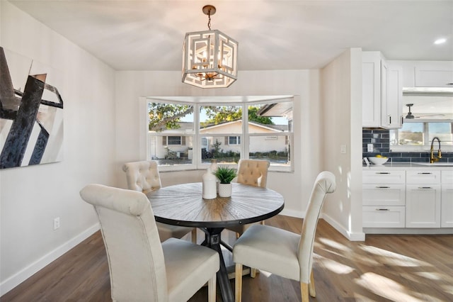 dining area with a notable chandelier, sink, and dark wood-type flooring