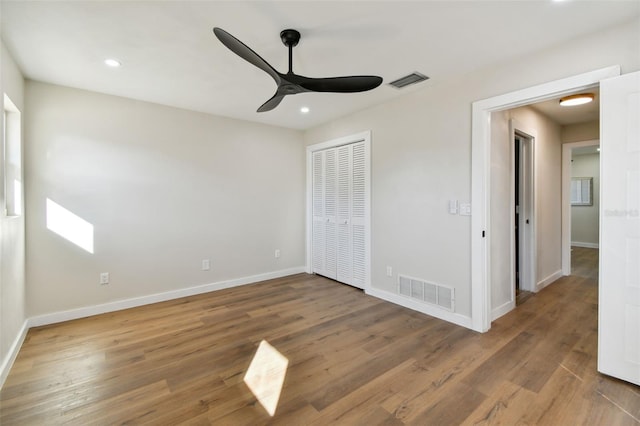 unfurnished bedroom with hardwood / wood-style floors, ceiling fan, and a closet