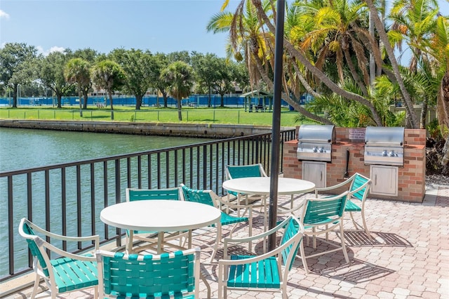 view of patio with exterior kitchen, a grill, and a water view