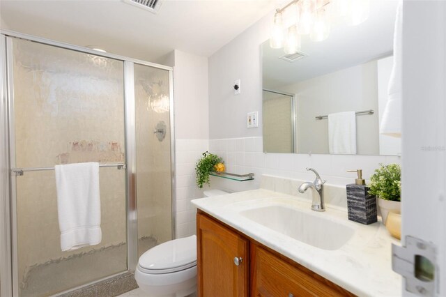 bathroom featuring tile walls, a shower with door, backsplash, toilet, and vanity