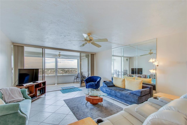 tiled living room with a textured ceiling, ceiling fan, and a wall of windows