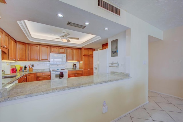 kitchen featuring a tray ceiling, ceiling fan, white appliances, and light stone counters