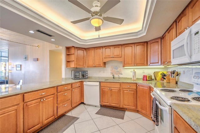 kitchen with white appliances, ceiling fan, ornamental molding, a tray ceiling, and light stone countertops