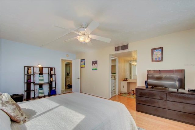 bedroom featuring ceiling fan with notable chandelier, ensuite bathroom, and light hardwood / wood-style flooring