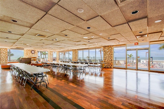 unfurnished dining area featuring a drop ceiling and hardwood / wood-style flooring