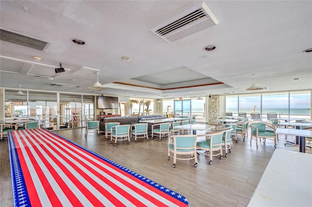 interior space featuring a textured ceiling, a raised ceiling, a healthy amount of sunlight, and a water view