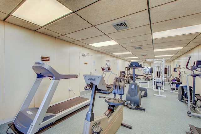 workout area with a paneled ceiling and light colored carpet