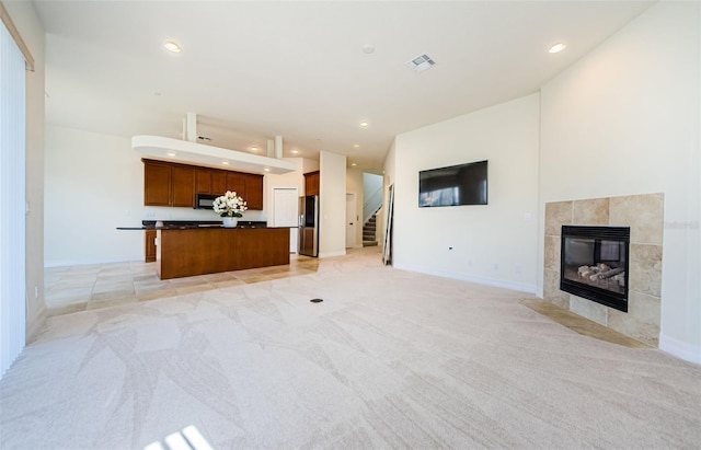 unfurnished living room with a tile fireplace and light colored carpet