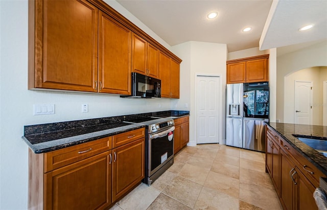 kitchen with dark stone countertops, light tile floors, and stainless steel appliances