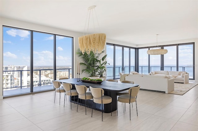 dining room featuring plenty of natural light, a water view, light tile flooring, and a wall of windows