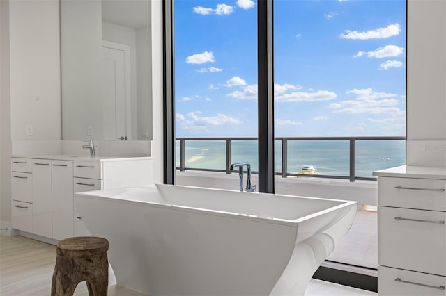 kitchen featuring a water view, white cabinets, a breakfast bar, and sink