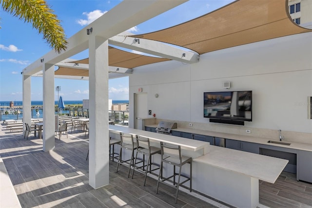 view of patio featuring an outdoor wet bar, grilling area, and a water view