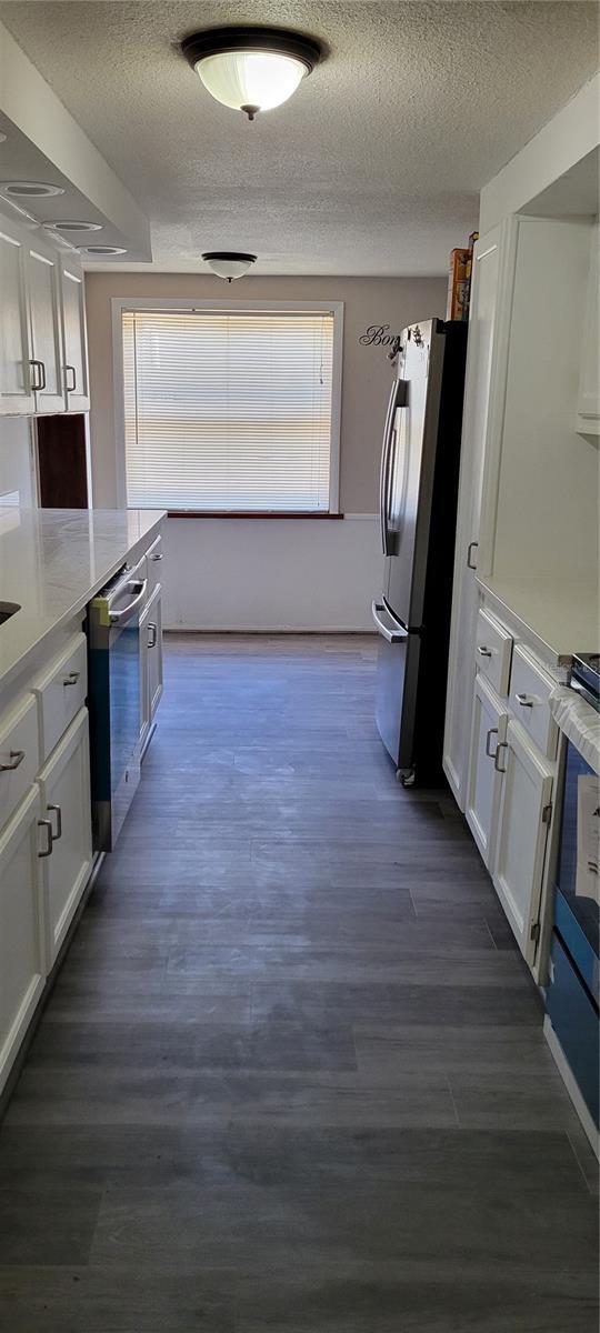 kitchen with white cabinetry, appliances with stainless steel finishes, dark wood-type flooring, and a textured ceiling