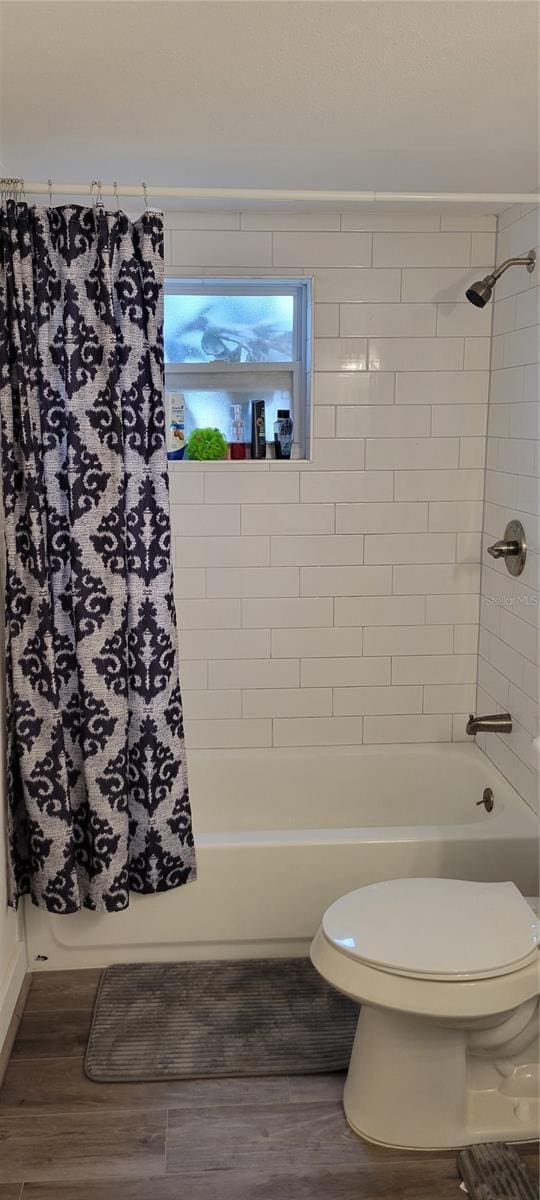 bathroom featuring shower / bath combination with curtain, wood-type flooring, and toilet