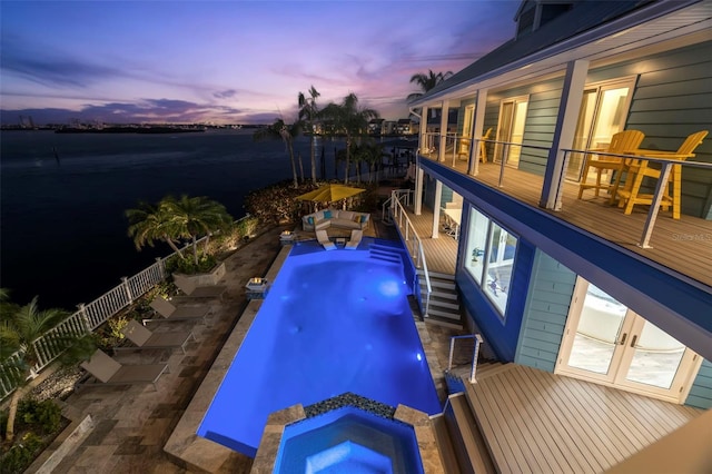 pool at dusk with an in ground hot tub and french doors