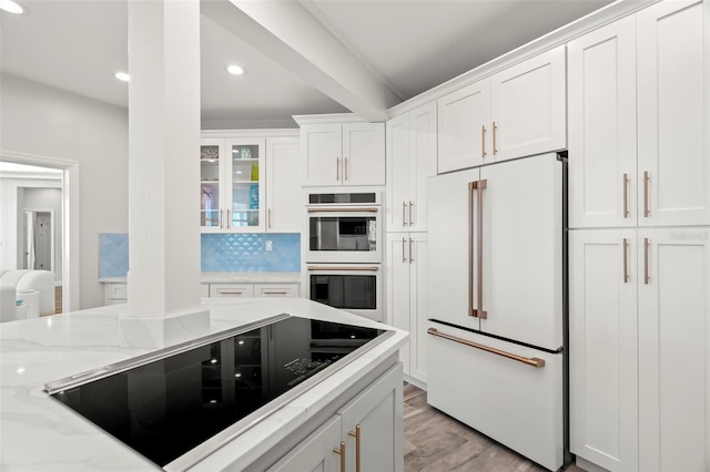 kitchen with light stone counters, black electric cooktop, high end white refrigerator, double oven, and white cabinets