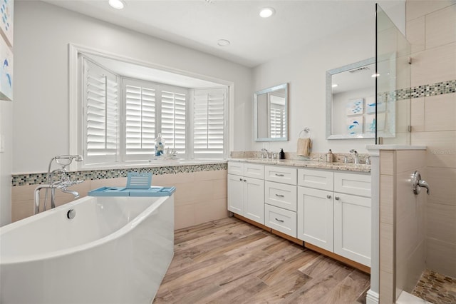 bathroom with wood-type flooring, vanity, and shower with separate bathtub