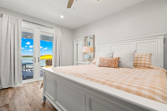 bedroom featuring access to exterior, ceiling fan, light hardwood / wood-style flooring, and a water view