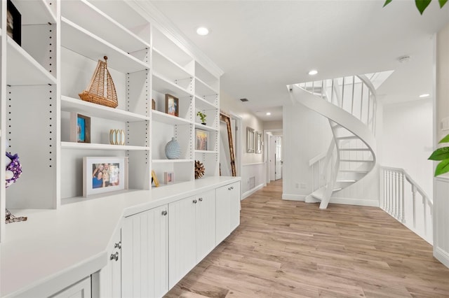 corridor with light hardwood / wood-style flooring and ornamental molding