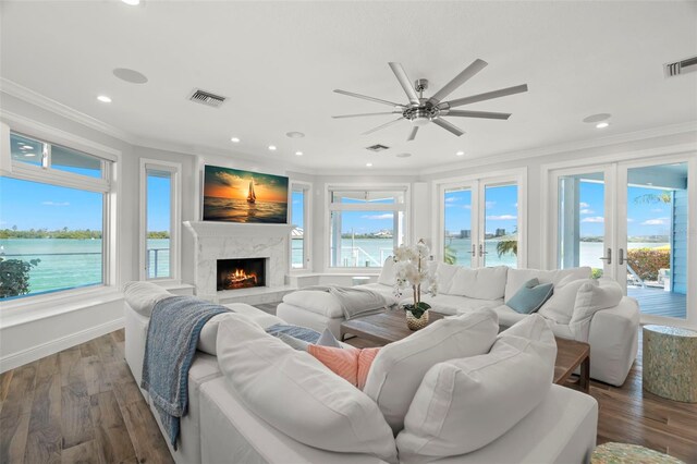 living room featuring a high end fireplace, french doors, dark hardwood / wood-style floors, ceiling fan, and ornamental molding